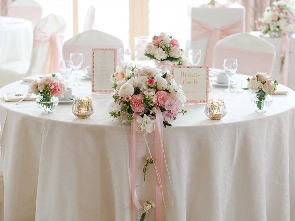 Der Festsaal des Restaurants im Altmühltal ist geschmückt für eine Hochzeit mit Blumen, Kränzen, Karten und Schleifen