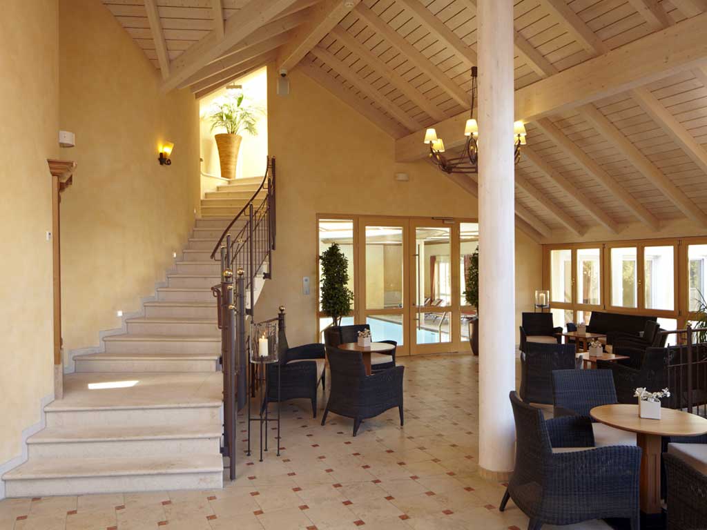 Der Loungebereich des Wellnesshotels im Altmühltal bietet Plätze zum Verweilen auf gemütlichen Sesseln mit Blick auf den Indoorpool
