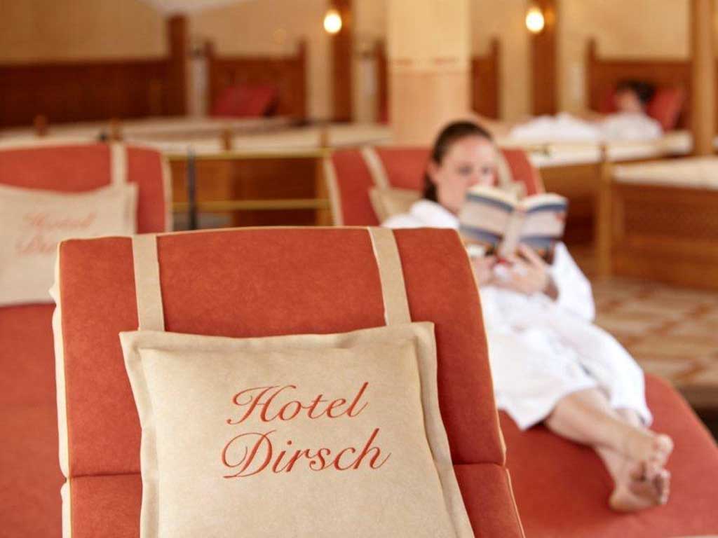 Eine Frau entspannt im Ruhebereich des Hotel Dirsch, liegt auf einer Liege und liest ein Buch